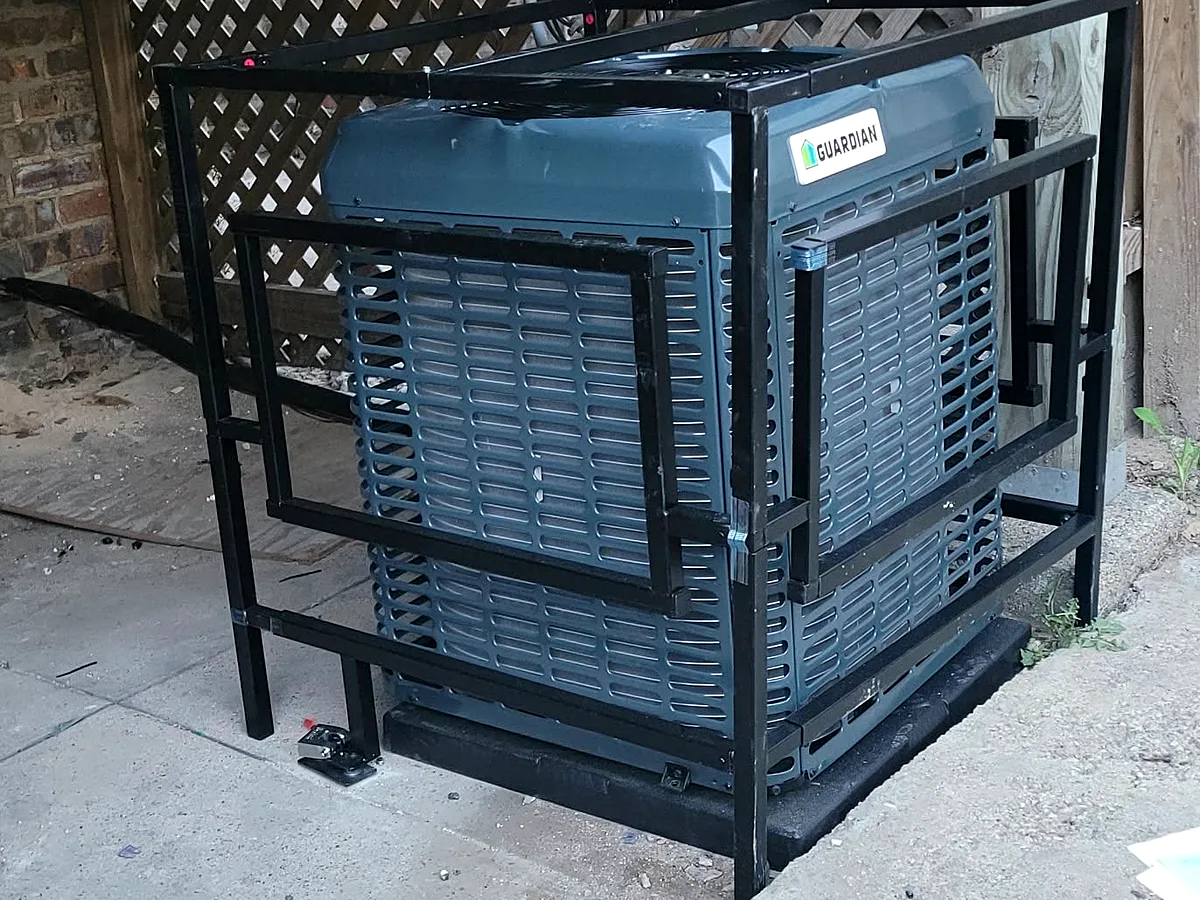 An outdoor air conditioner inside a black steel cage under a wooden deck