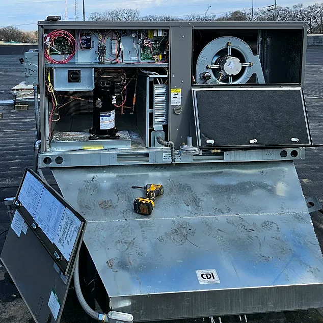 A commercial rooftop unit with its panels open, showing the compressor, wiring and blower fan, on a flat roof